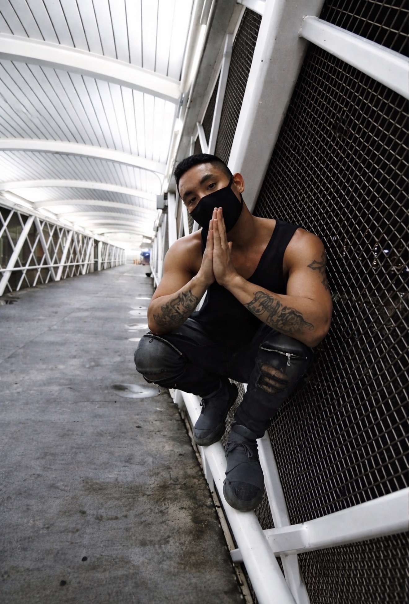 Masked man crouching in a white pedestrian walkway