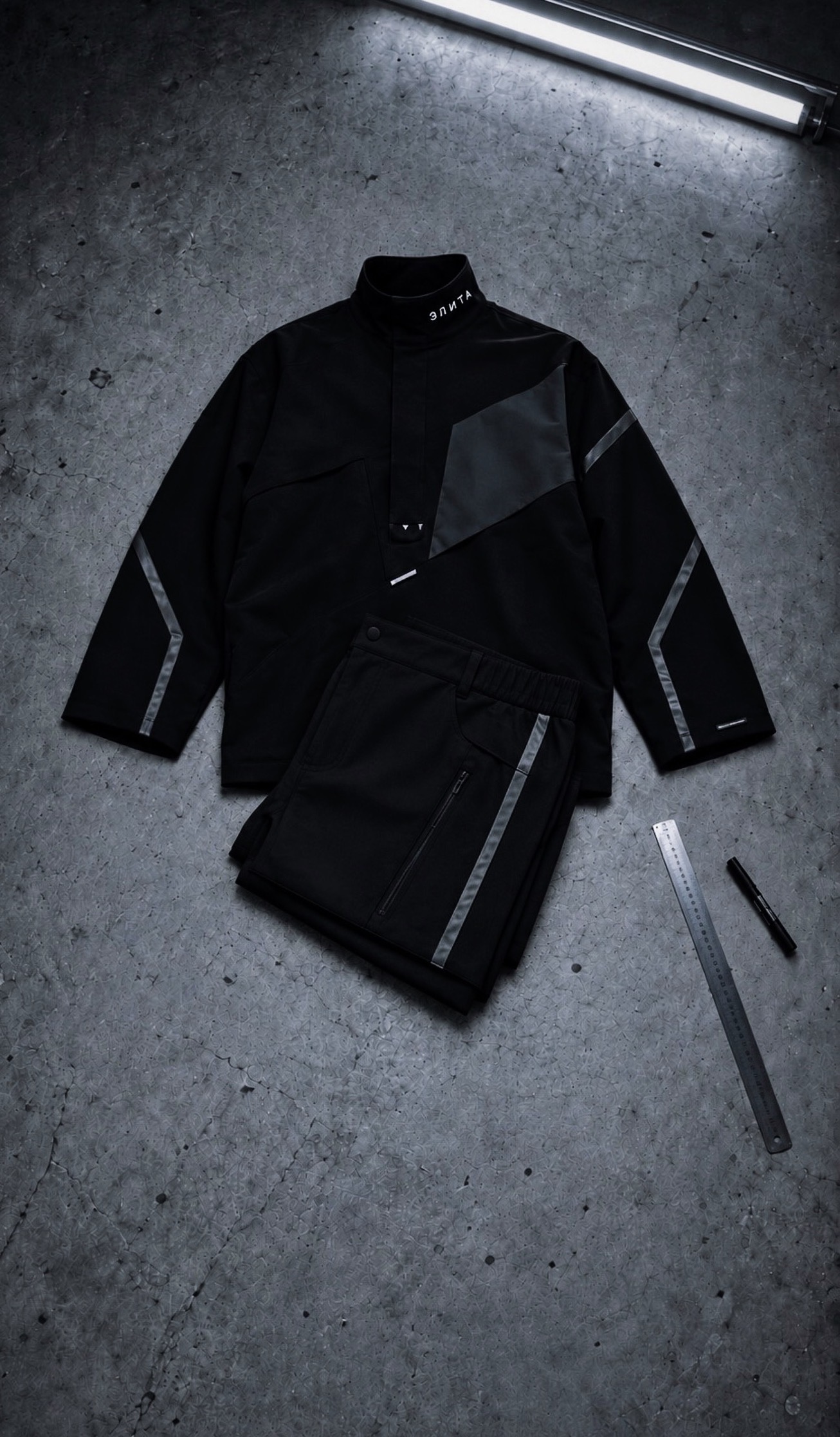 Black technical outfit with angular panels and reflective detailing